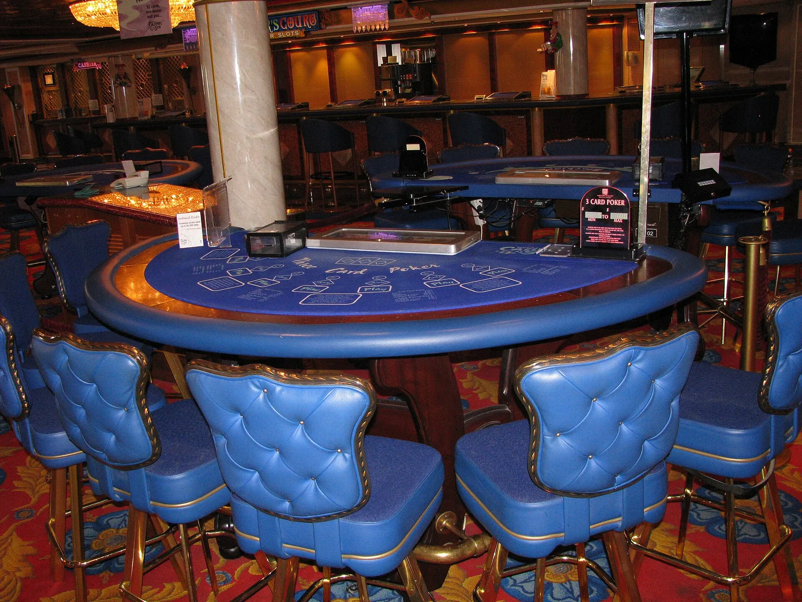 A three card poker table and tall blue stools in the casino of a cruise ship