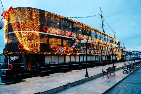 A ship at the quay covered in holiday lights and candy cane decorations at dusk